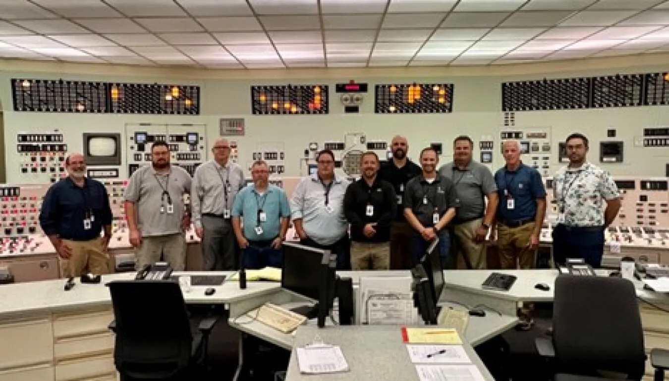 Members of the Palisades operations team stand together in front of the control boards in the plant's main control room.
